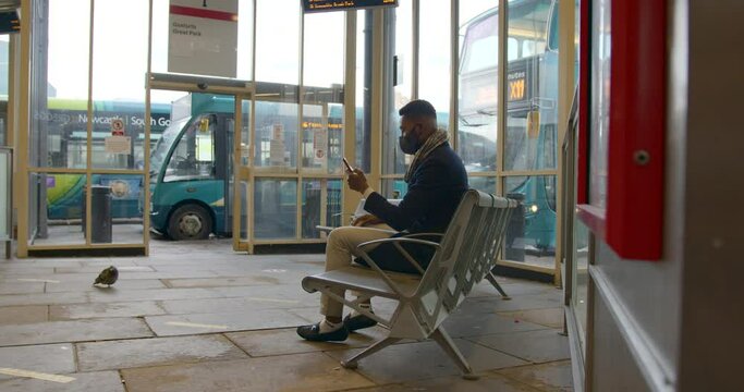 Man With Face Covering Using Phone in Bus Station
