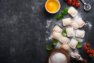 Ravioli Italian food. Tasty homemade with flour, tomatoes, eggs and greens basil on dark background. Food cooking ingredients background. Top view.