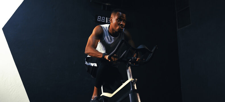 Sporty African-american man cardio with exercise bike burning calories with in the fitness gym fit body healthy lifestyle, Athlete muscle building strong concept.