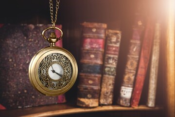 Antique pocket watch on opened old book on background.