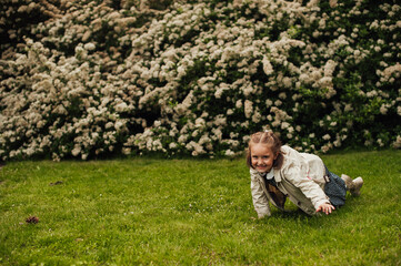 Naklejka na ściany i meble pretty little girl with a smile on a face is crawling on the grass 