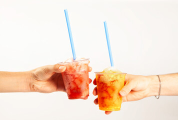 Hands holding two flavoured slush frozen drinks with straws - obrazy, fototapety, plakaty