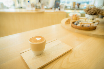 Close up cup of coffee with Cappuccino or latte art milk foam surface on wooden table. Image top of view.