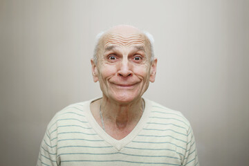 Portrait of smiling grey haired man isolated on beige background. Human emotions concept.
