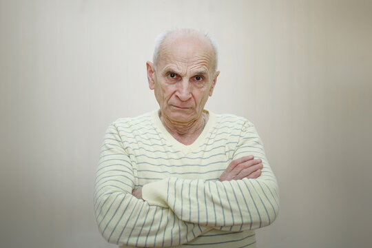 Senior man with serious look posing with crossing hands inside. Angry grandpa portrait.