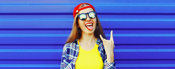 Portrait of happy cheerful young woman showing her tongue having fun wearing red baseball cap on...
