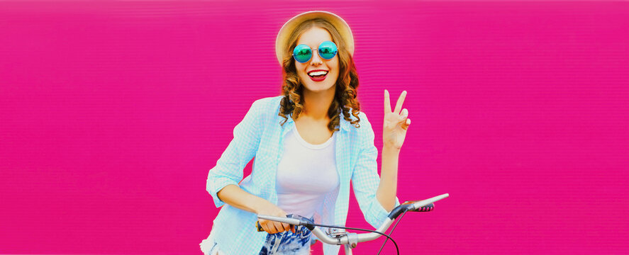 Summer colorful image of happy smiling young woman with bicycle on vivid pink background