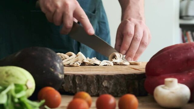 man's hand slicing champignons on a chopping board