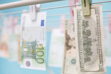 Dollar and euro banknotes weigh on a clothes dryer. Money laundering concept.