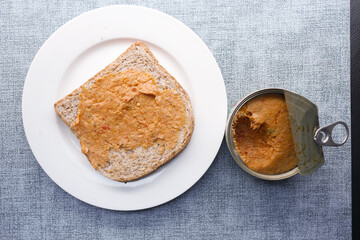 spreading canned tuna on a toasted bread 