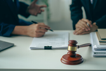 Male attorneys or judges consult teams with clients, business and legal services. The consultant presents the contract signed with the hammer placed in front and concept of justice and lawyer