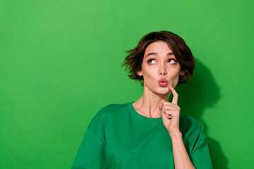 Portrait of minded pretty lady finger touch pouted lips look interested empty space isolated on green color background