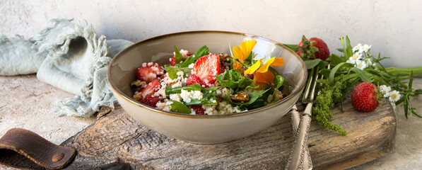 plate with salad with spinach, couscous and strawberries on the table