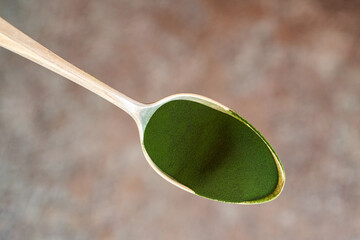 Green chlorella algae powder on a metal spoon