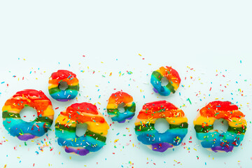 summer funny creative concept of donuts with sprinkles and icing rainbow colors over background, copy space