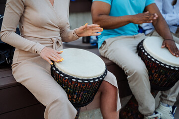 A beautiful girl plays the djemba, women's hands hit the drum, street performers, close-up.