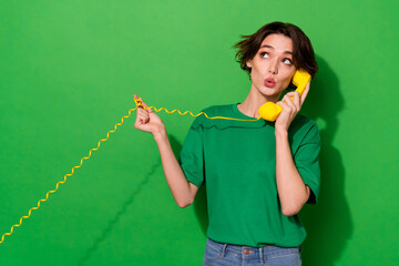 Photo of dreamy funky lady wear spring outfit looking empty space talking phone isolated green color background
