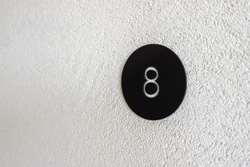 White number eight in a black circle on a white plaster wall