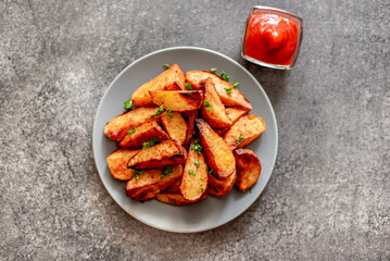 Baked potato wedges with herbs and sauce on stone background - homemade organic vegetable veggie veggie potato wedge appetizer.
