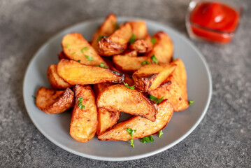 Baked potato wedges with herbs and sauce on stone background - homemade organic vegetable veggie veggie potato wedge appetizer.