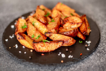 Baked potato wedges with herbs and sauce on stone background - homemade organic vegetable veggie veggie potato wedge appetizer.
