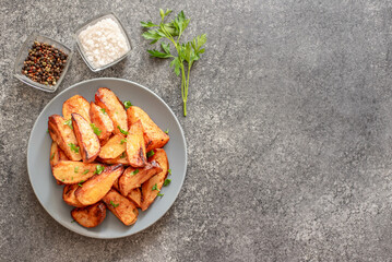 Baked potato wedges with herbs and sauce on stone background - homemade organic vegetable veggie veggie potato wedge appetizer with copy space for your text