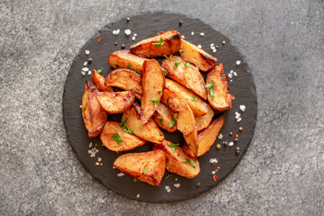 Baked potato wedges with herbs and sauce on stone background - homemade organic vegetable veggie veggie potato wedge appetizer.