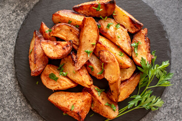 Baked potato wedges with herbs and sauce on stone background - homemade organic vegetable veggie veggie potato wedge appetizer.