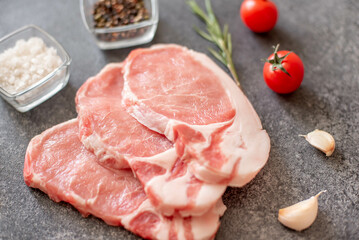 raw pork steaks with spices on a stone background