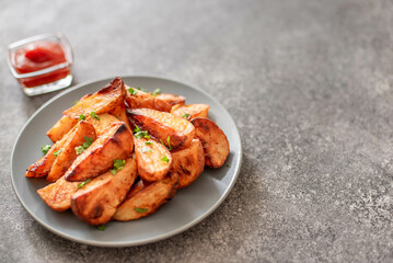 Baked potato wedges with herbs and sauce on stone background - homemade organic vegetable veggie veggie potato wedge appetizer with copy space for your text