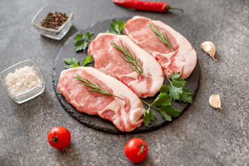 raw pork steaks with spices on a stone background