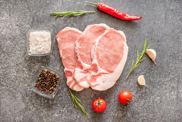 raw pork steaks with spices on a stone background