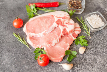 raw pork steaks with spices on a stone background