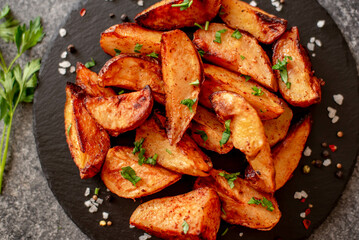 Baked potato wedges with herbs and sauce on stone background - homemade organic vegetable veggie veggie potato wedge appetizer.