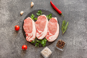 raw pork steaks with spices on a stone background