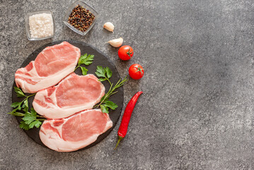 raw pork steaks with spices on stone background with copy space for your text
