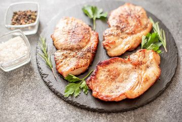 grilled pork steaks with spices on stone background