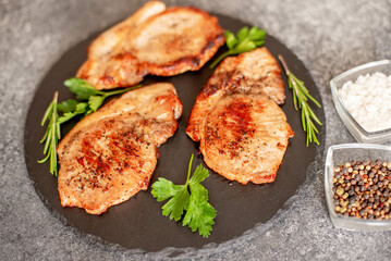 grilled pork steaks with spices on stone background
