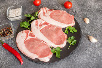 raw pork steaks with spices on a stone background