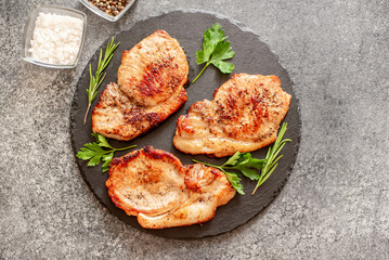 grilled pork steaks with spices on stone background