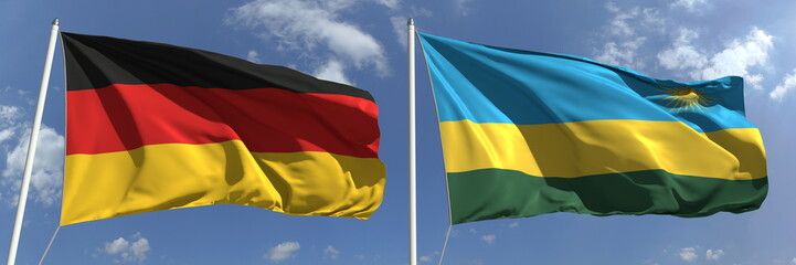 Flags of Germany and Rwanda on flagpoles. 3d rendering