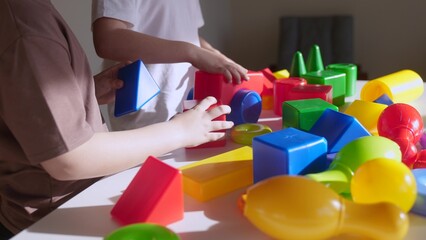 kids girl and baby play in kindergarten. a group of children play toys cubes and cars on the table in indoor kindergarten. happy family preschool education concept. nursery boy baby toddler home