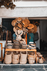 Traditional village store with hats and straw bags, baskets and clothes on the street. Handmade...