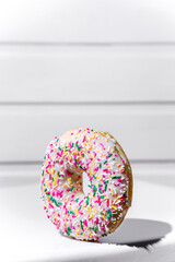 Sweet donut with white frosting and sprinkling