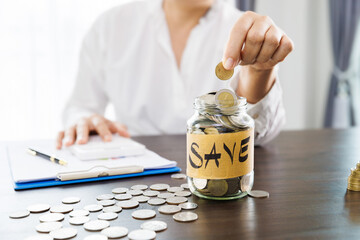 Pile of coins in a bottle on the table and woman picking up a coin for save money, saving money or savings concept.