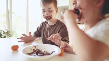 Obraz na płótnie Canvas baby boy and girl eat chocolate. dirty little baby kids in the kitchen eating chocolate in the morning lifestyle. happy family eating sweets kid dream concept. baby dirty face eating chocolate cocoa