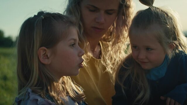 Mom with two little daughters bonding and spending time together at the meadow. Shot with RED helium camera in 4K.     
