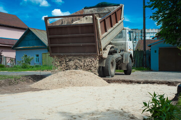 Fototapeta na wymiar Dump trucks carrying good filling a field, giving rise to a fine soil. Preparation and construction.