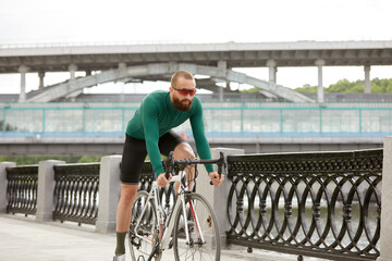 The young man rides a bicycle along the river embankment. A cyclist riding a bike around the city. Outdoor vacation concept.