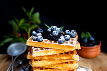 Waffles with fresh blueberries and powdered sugar on the rustic table. Freshly made Belgian waffles